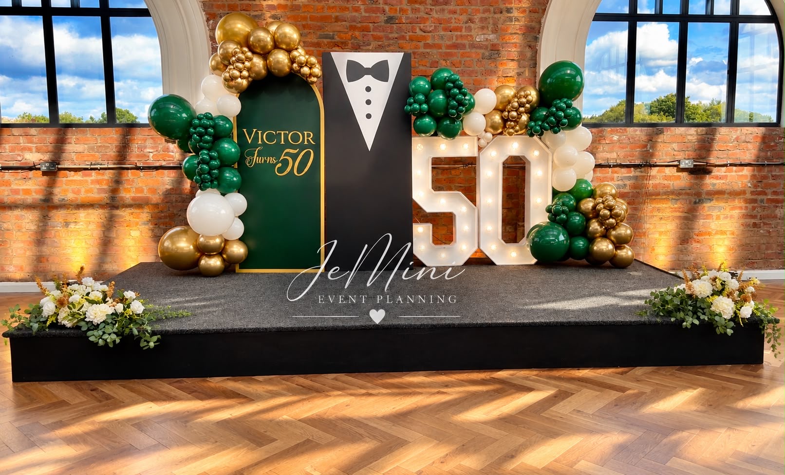 Victor's 50th birthday stage with marquee numbers and green-and-gold balloon garland, styled by Jeminii Event Styling in Manchester