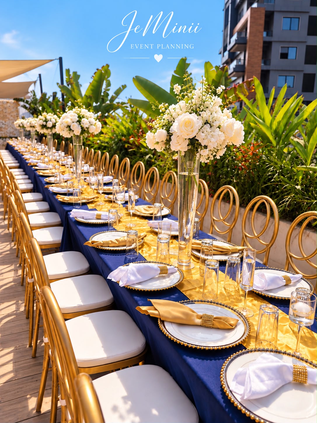 Long wedding banquet table with navy linen, gold place settings and tall white floral arrangements, styled by Jeminii Event Styling in Freetown, Sierra Leone