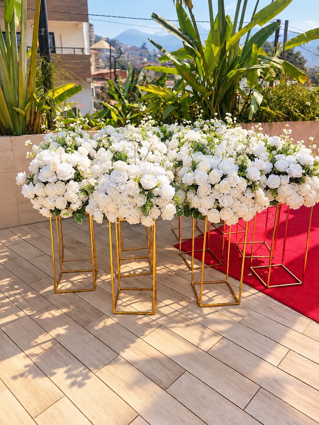 White rose centrepieces displayed on tall gold stands for an outdoor wedding, styled by Jeminii Event Styling in Freetown, Sierra Leone